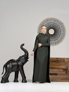  Woman wearing modest hunter green straight silhouette gown with cape in back.